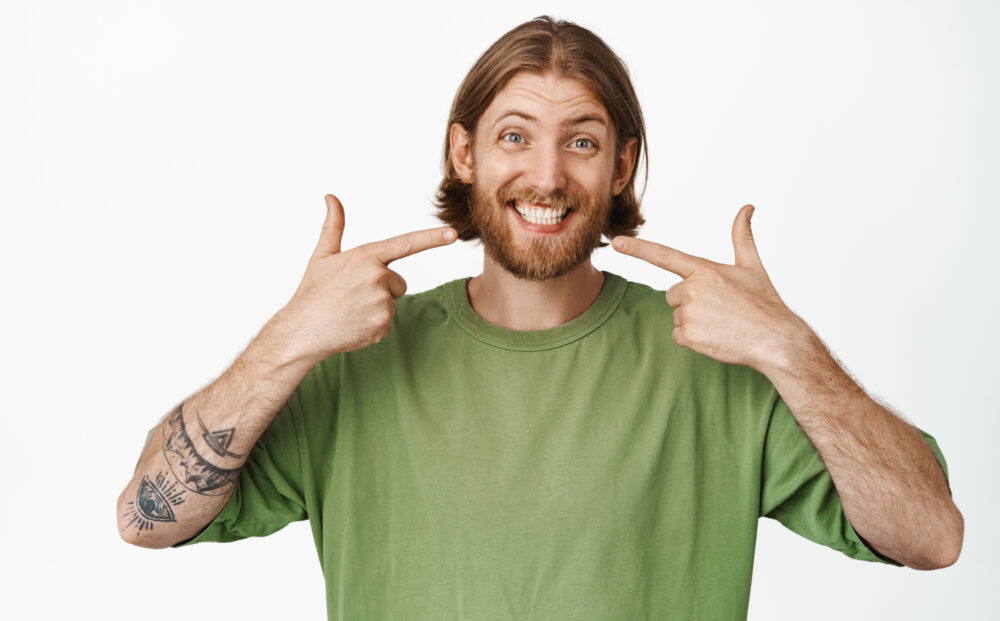 Stomatology,,Dental,Clinic.,Smiling,Handsome,Blond,Guy,,Caucasian,Man,Pointing